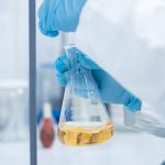 Quimico haciendo pruebas acercamiento manos y recipiente de laboratorio